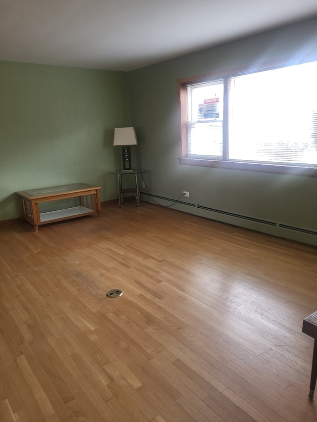 unfurnished room featuring a baseboard radiator and light wood finished floors