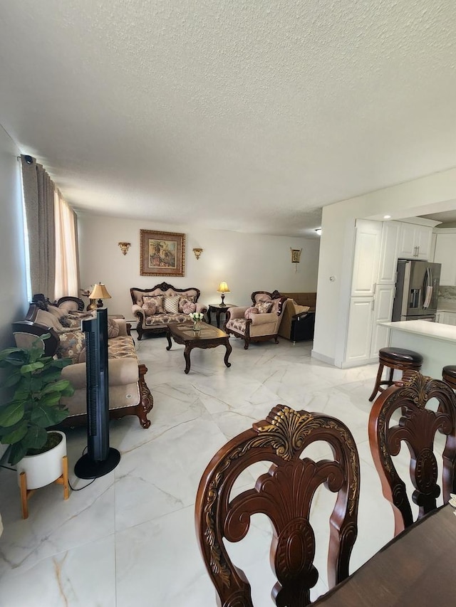 living room featuring marble finish floor and a textured ceiling