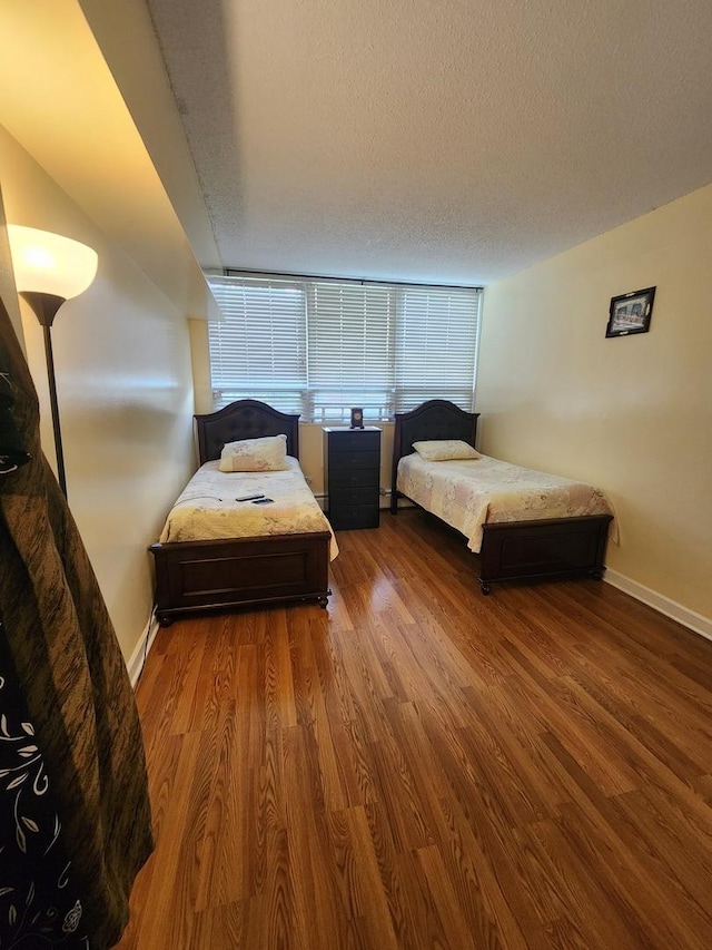 bedroom featuring a textured ceiling, baseboards, and wood finished floors