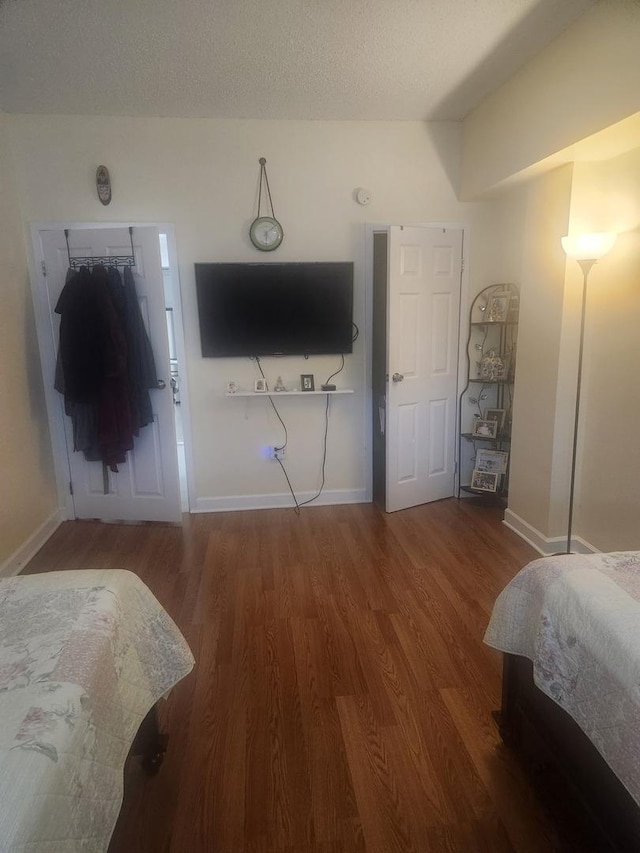 bedroom with a textured ceiling, wood finished floors, and baseboards