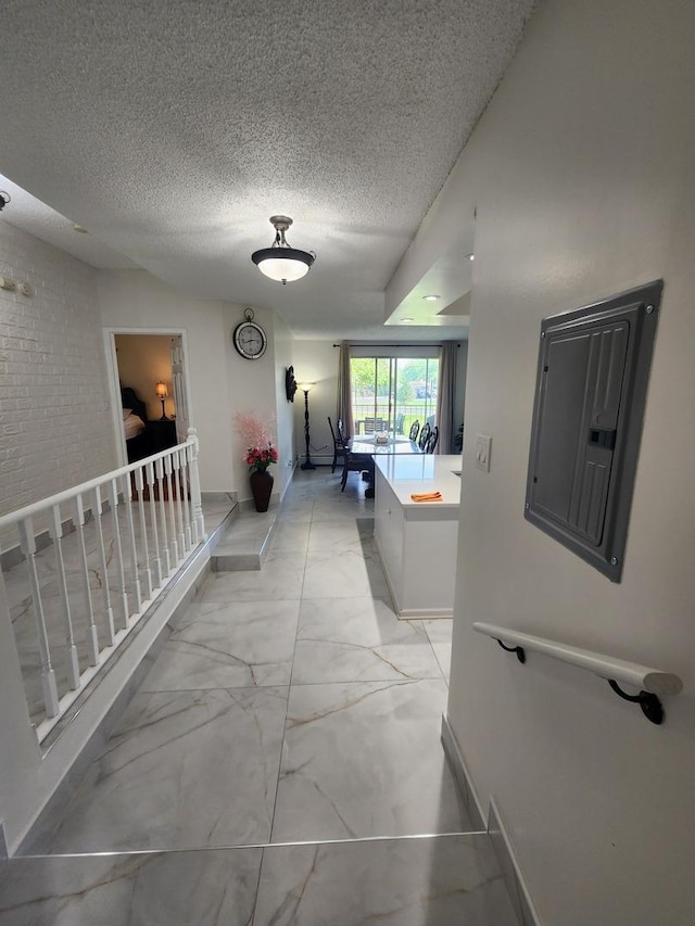 corridor featuring marble finish floor, electric panel, a textured ceiling, and baseboards