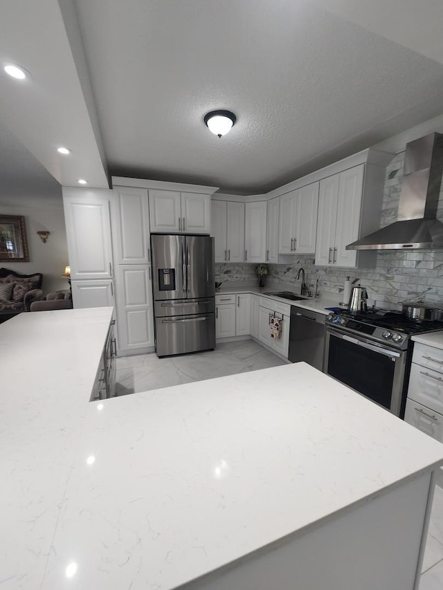 kitchen featuring stainless steel appliances, a sink, marble finish floor, light countertops, and wall chimney exhaust hood