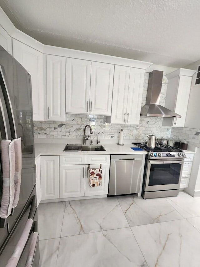 kitchen featuring wall chimney exhaust hood, appliances with stainless steel finishes, light countertops, and white cabinetry