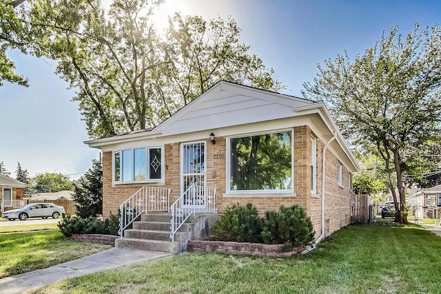 bungalow-style house with brick siding and a front lawn