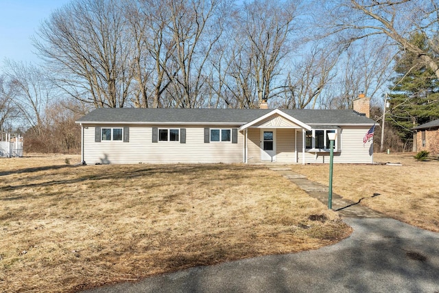 single story home featuring a porch, a chimney, and a front lawn