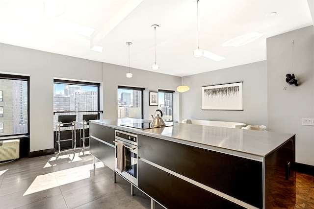 kitchen with black electric cooktop, stainless steel oven, light countertops, modern cabinets, and pendant lighting