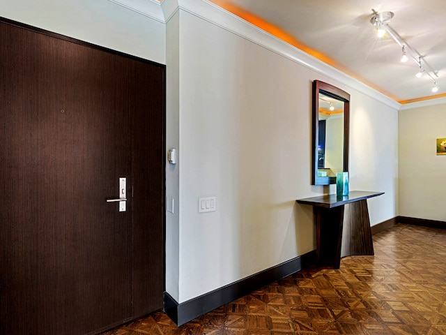 hallway featuring ornamental molding, rail lighting, and baseboards