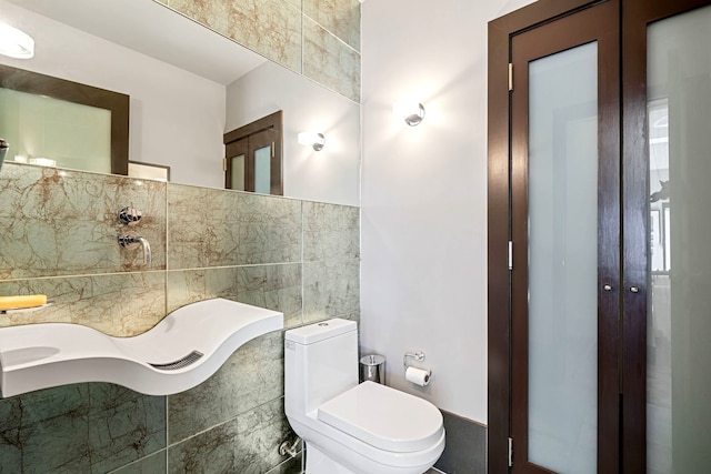 bathroom with tile walls and toilet