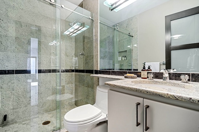 bathroom featuring vanity, a shower stall, and toilet