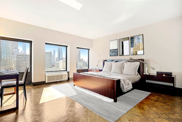 bedroom with an AC wall unit, a city view, and baseboards