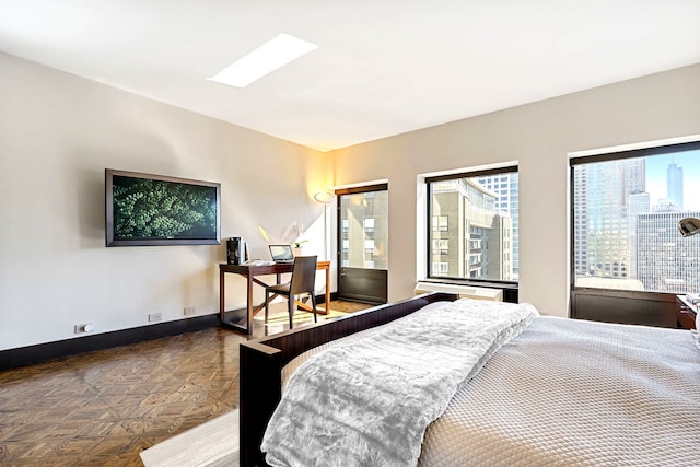 bedroom featuring multiple windows, baseboards, and a city view