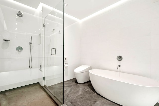 full bathroom with toilet, a freestanding tub, a shower stall, and tile walls