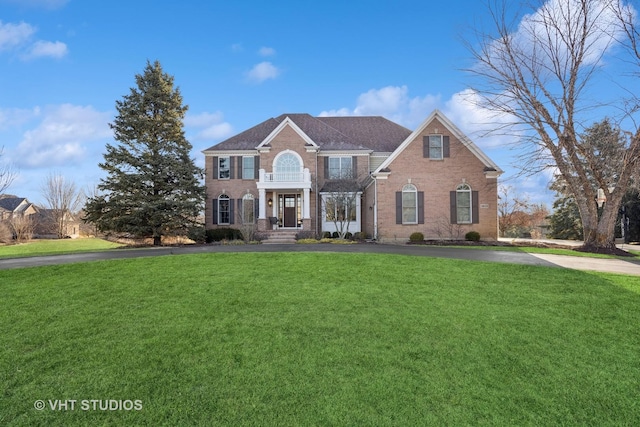 colonial-style house with aphalt driveway, brick siding, and a front lawn