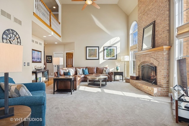 living room with visible vents, carpet, a fireplace, and a ceiling fan