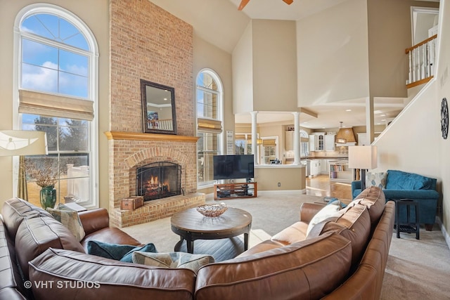 living area with carpet flooring, a brick fireplace, a high ceiling, and ceiling fan