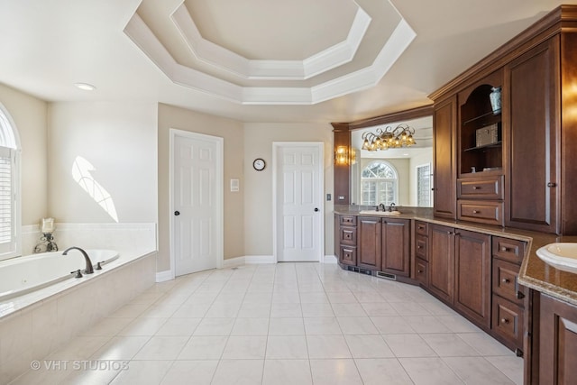 bathroom with a raised ceiling, a garden tub, vanity, and tile patterned flooring