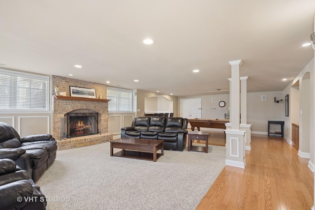 living room featuring recessed lighting, a brick fireplace, and ornate columns