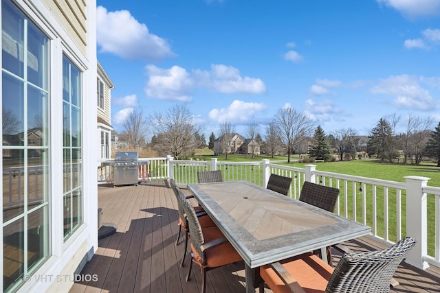 wooden terrace with a lawn, a grill, and outdoor dining area