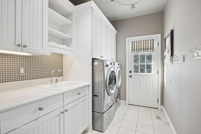 laundry room with a sink, washing machine and dryer, cabinet space, light tile patterned floors, and baseboards