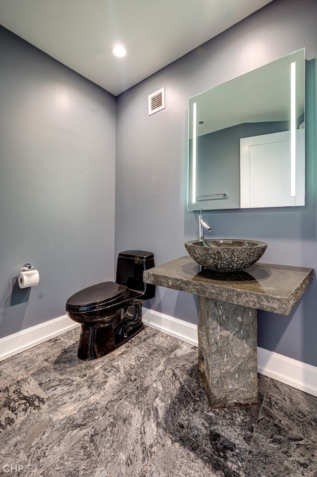 bathroom with baseboards, visible vents, a sink, toilet, and marble finish floor