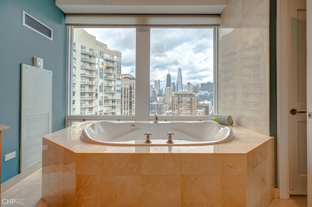 bathroom featuring a wealth of natural light, visible vents, a city view, and a garden tub