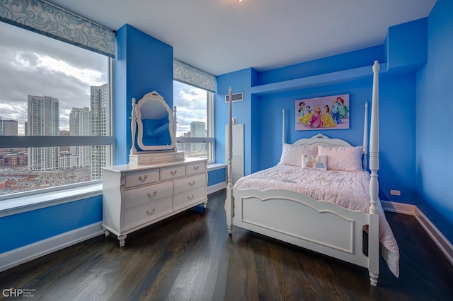 bedroom with visible vents, baseboards, a city view, and dark wood-style flooring