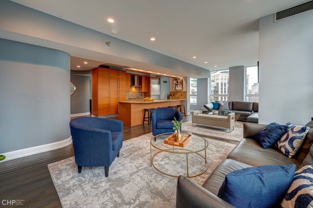 living area with dark wood-style floors, visible vents, recessed lighting, and baseboards