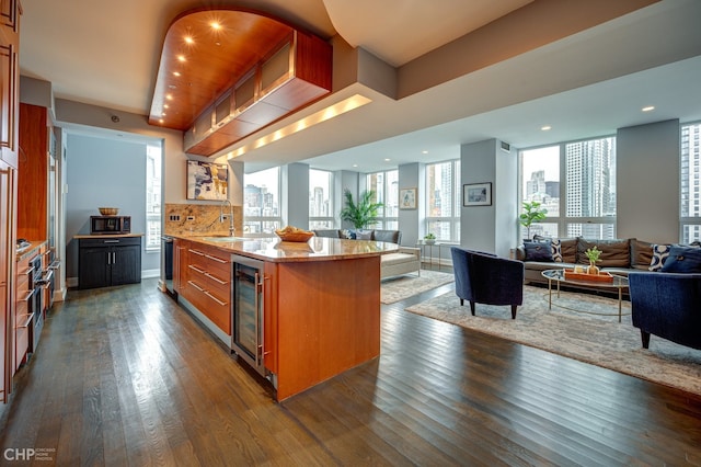 kitchen featuring dark wood-style floors, beverage cooler, brown cabinets, stainless steel microwave, and open floor plan