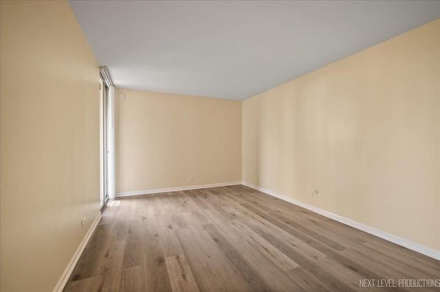 spare room featuring baseboards and wood finished floors