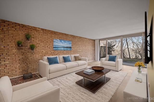 living area featuring brick wall and wood finished floors