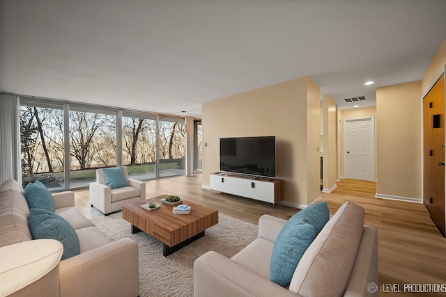 living area with recessed lighting, baseboards, visible vents, and light wood finished floors