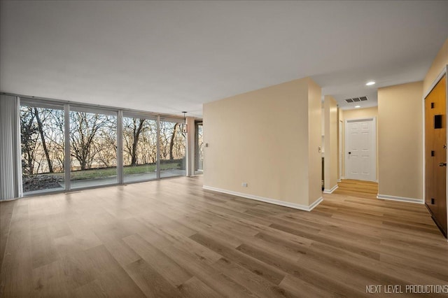 empty room with visible vents, baseboards, and wood finished floors