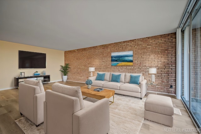 living area with brick wall, light wood-style flooring, and baseboards