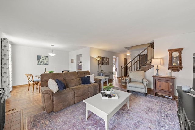 living room featuring stairs, wood finished floors, and baseboards