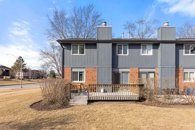 back of house with a yard, a chimney, a deck, and brick siding