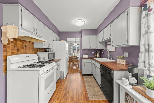 kitchen featuring light wood-style flooring, backsplash, a sink, white appliances, and under cabinet range hood