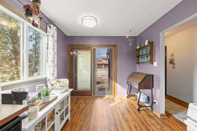 dining room featuring a chandelier, plenty of natural light, baseboards, and wood finished floors