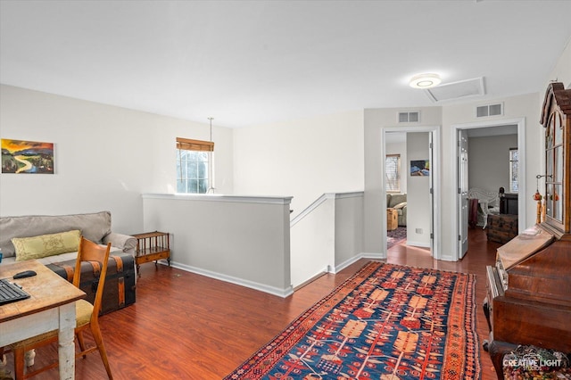 hallway with attic access, visible vents, wood finished floors, and an upstairs landing