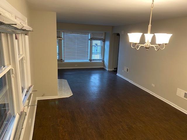 spare room featuring a notable chandelier, baseboards, and wood finished floors