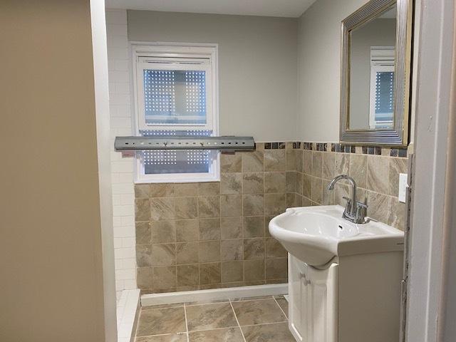 bathroom featuring wainscoting, tile patterned flooring, vanity, and tile walls