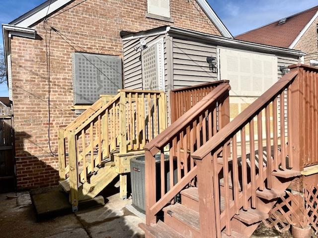 exterior space with brick siding, central AC, and stairs