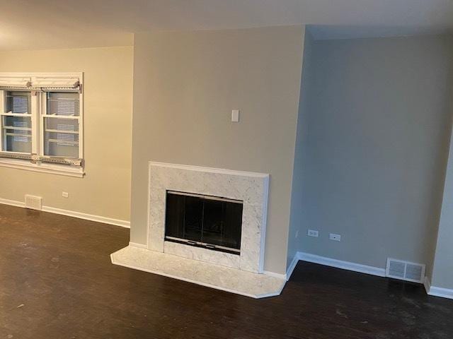 details with visible vents, wood finished floors, a high end fireplace, and baseboards