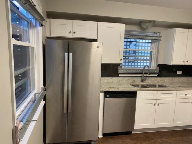 kitchen featuring stainless steel appliances, light stone counters, a sink, and white cabinets