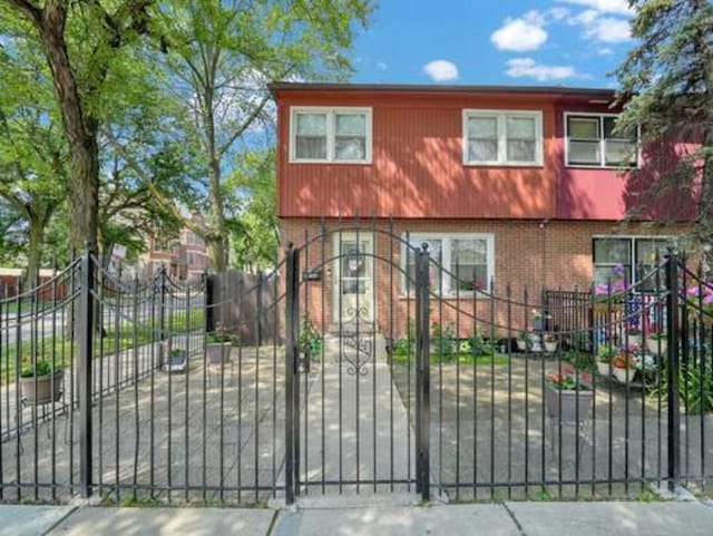 view of front of property featuring a fenced front yard, a gate, and brick siding