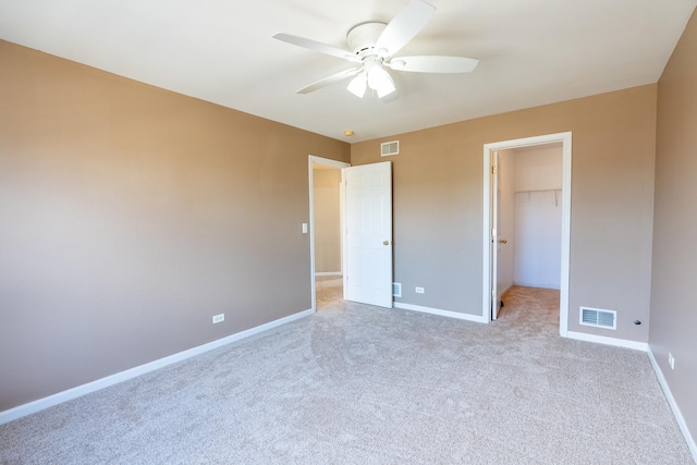 unfurnished bedroom featuring a spacious closet, visible vents, carpet, and baseboards