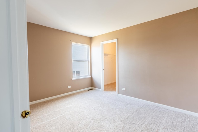 empty room with carpet flooring, visible vents, and baseboards