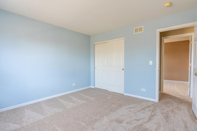 unfurnished bedroom with a closet, visible vents, baseboards, and carpet