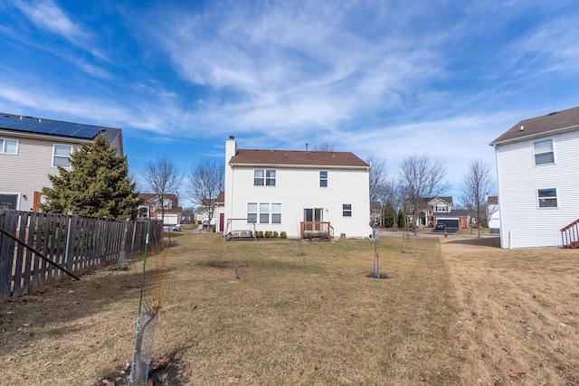 back of house featuring fence, a lawn, and a chimney