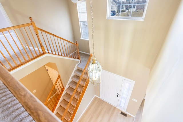 stairway featuring visible vents, a towering ceiling, and wood finished floors