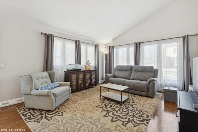 living area featuring high vaulted ceiling, wood finished floors, visible vents, and baseboards